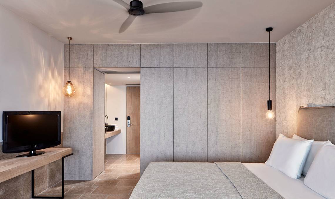 Schlafzimmer des Minos Palace Hotel & Suites mit Fernseher, Bett und Einbauschränken