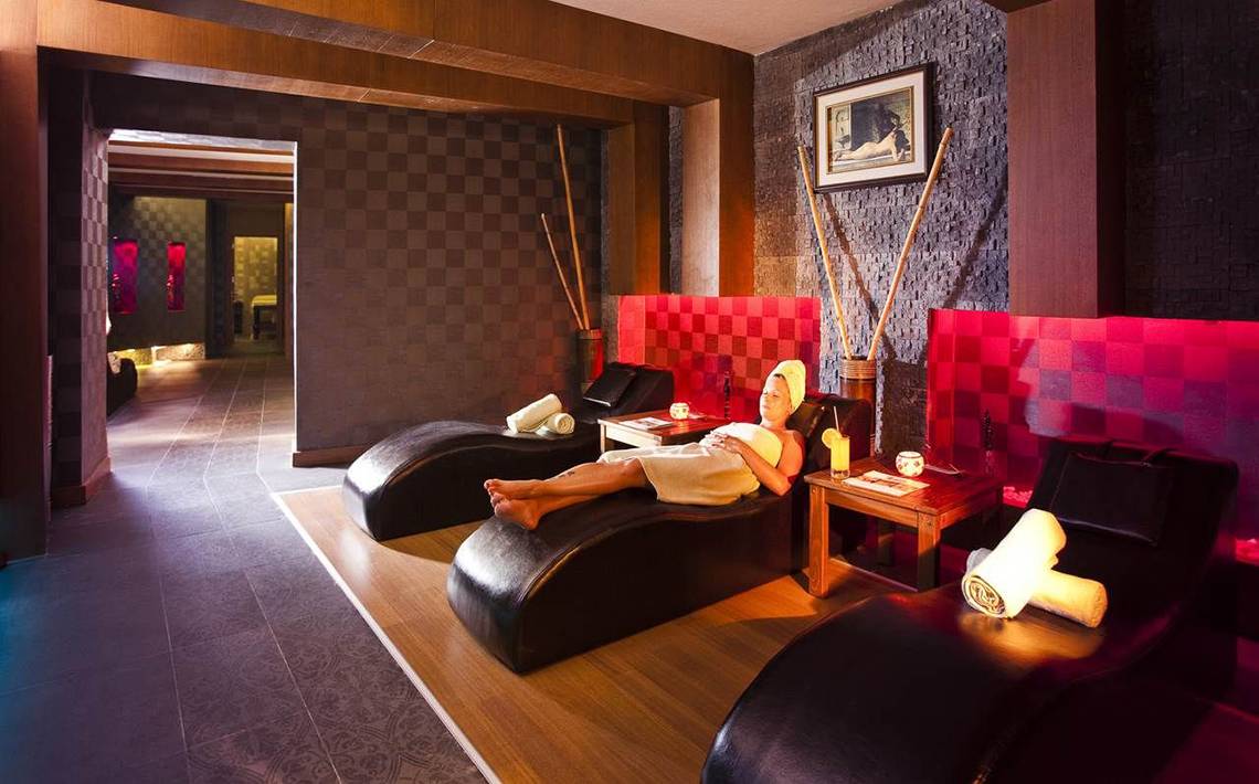 Loungebereich im Side Sun Hotel mit roten und schwarzen Möbeln und einer Frau, die sich entspannt.