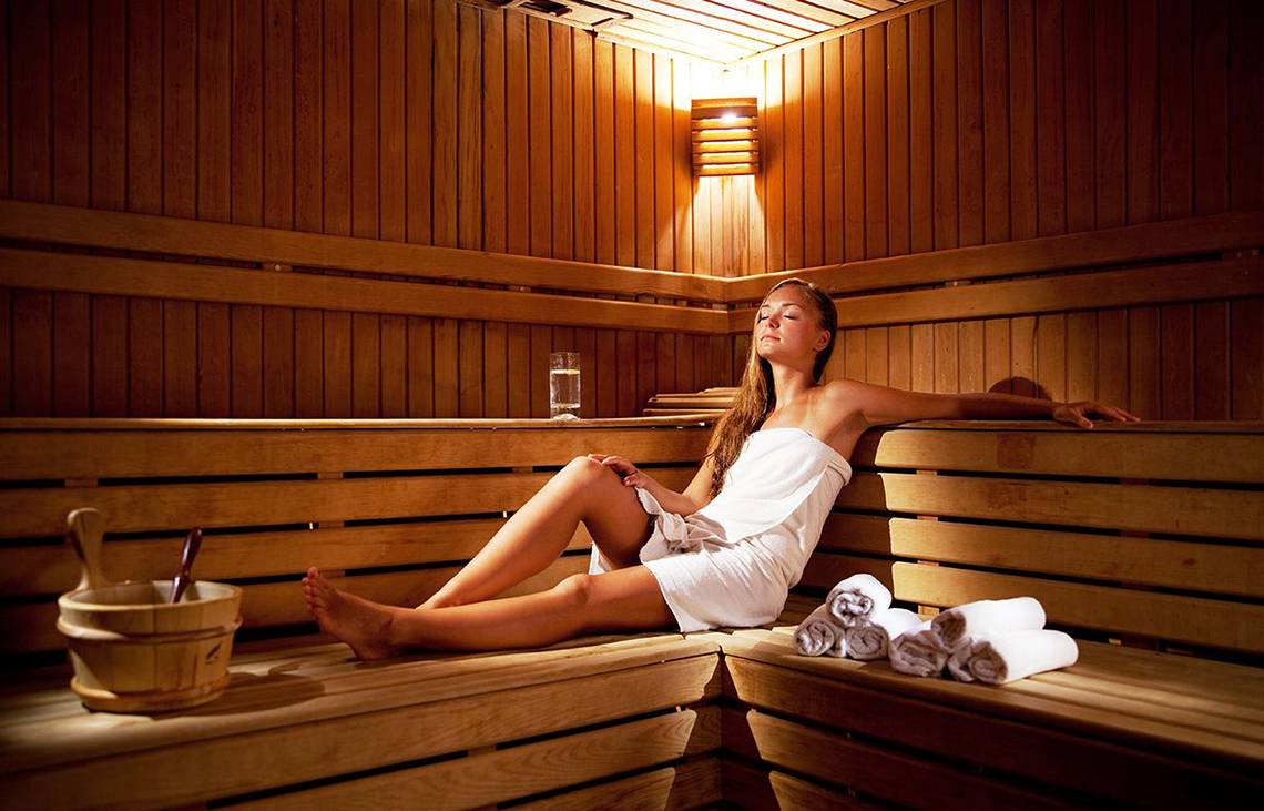 Eine Frau im weißen Badetuch sitzt entspannt in der Sauna des Side Sun Hotels.
