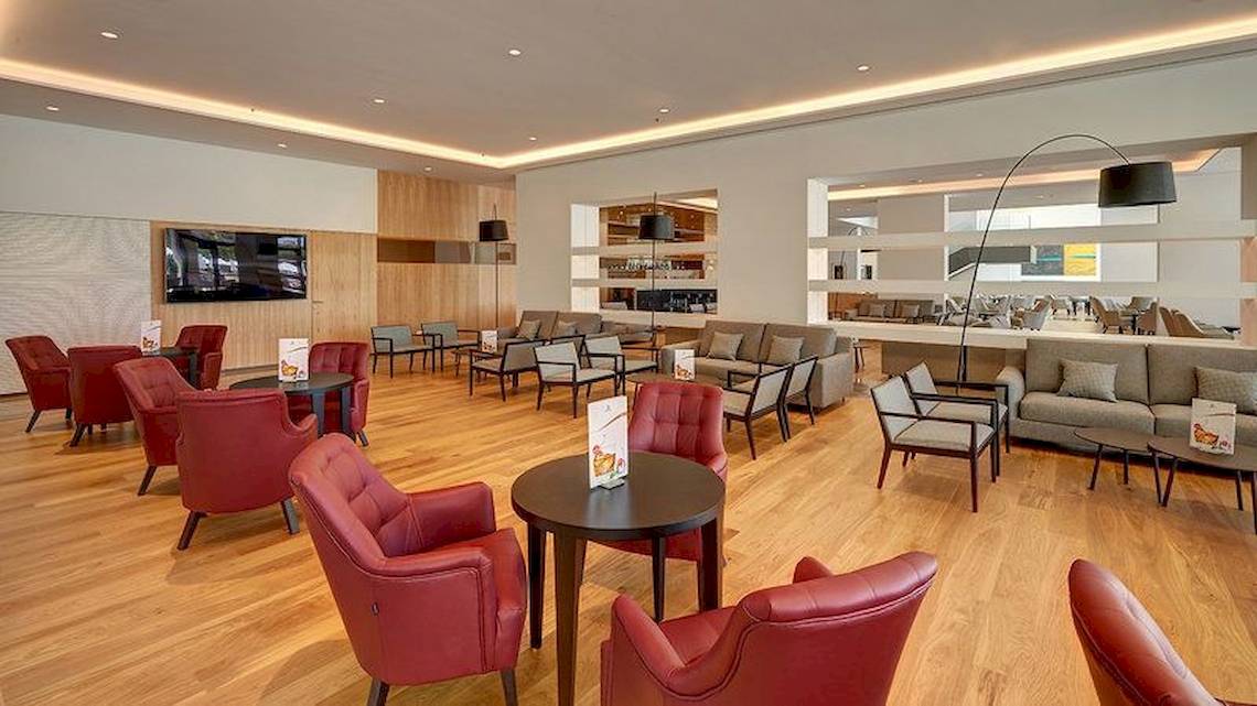 Lobby des Hipotels Playa de Palma Palace mit roten Stühlen, Tischen und Sofas.