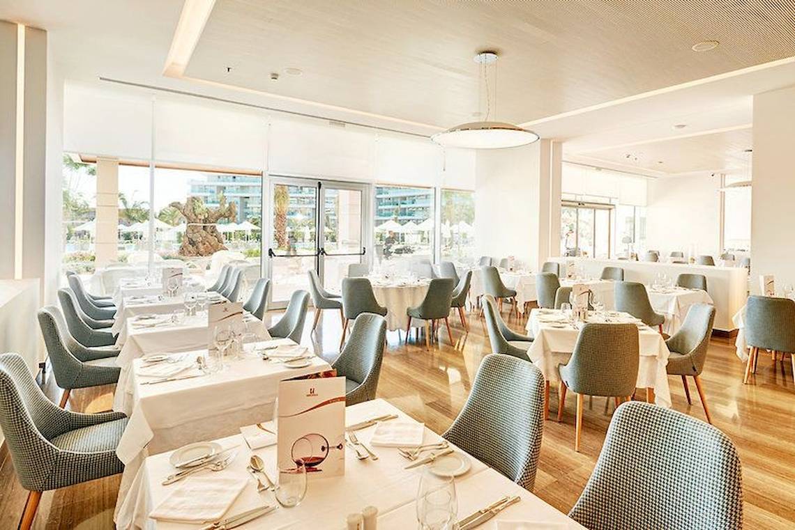 Innenansicht des Restaurants im Hipotels Playa de Palma Palace mit gedeckten Tischen und Stühlen.