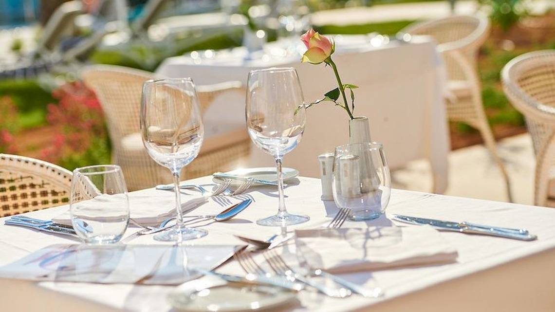 Essen-Tisch im Hipotels Playa de Palma Palace mit Gläsern, Besteck und einer Rose in einer Vase.