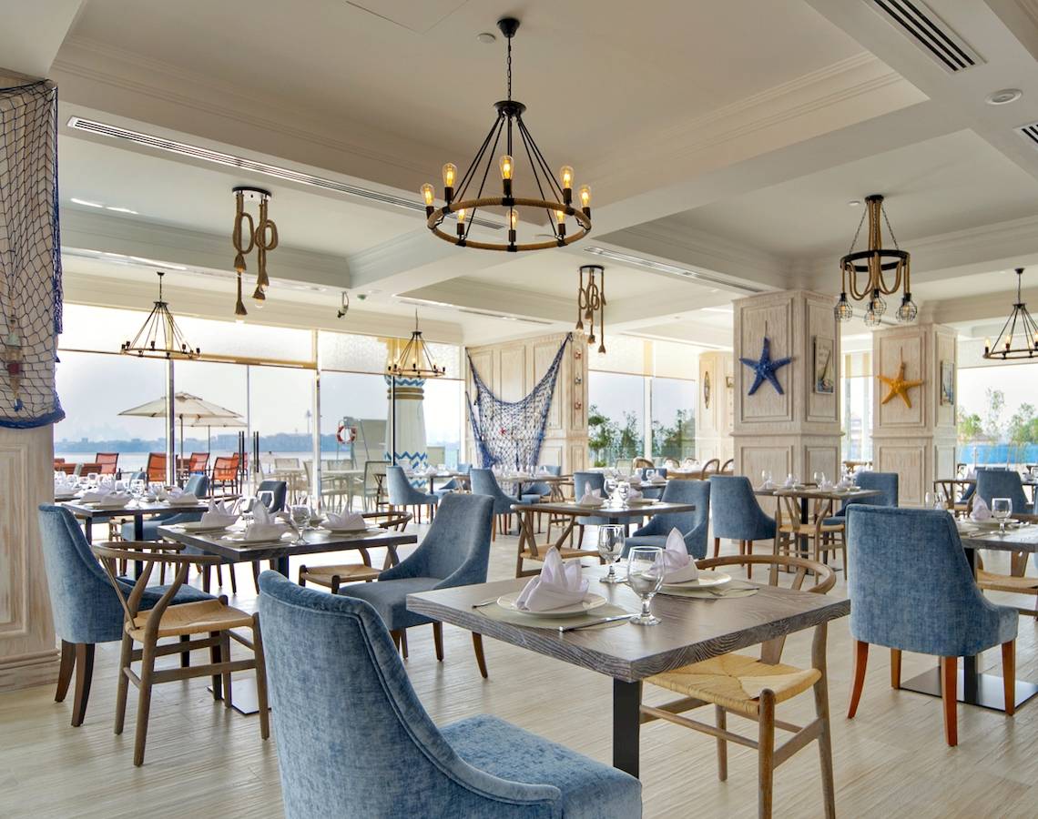Restaurant im Royal Central Hotel The Palm mit blauen Stühlen und Tischen.