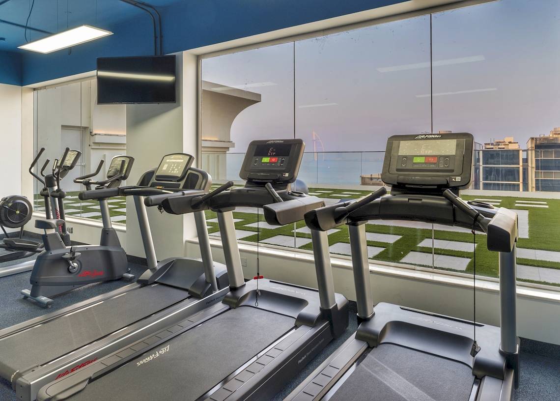 Fitnessraum im Royal Central Hotel The Palm mit Blick auf die Skyline.