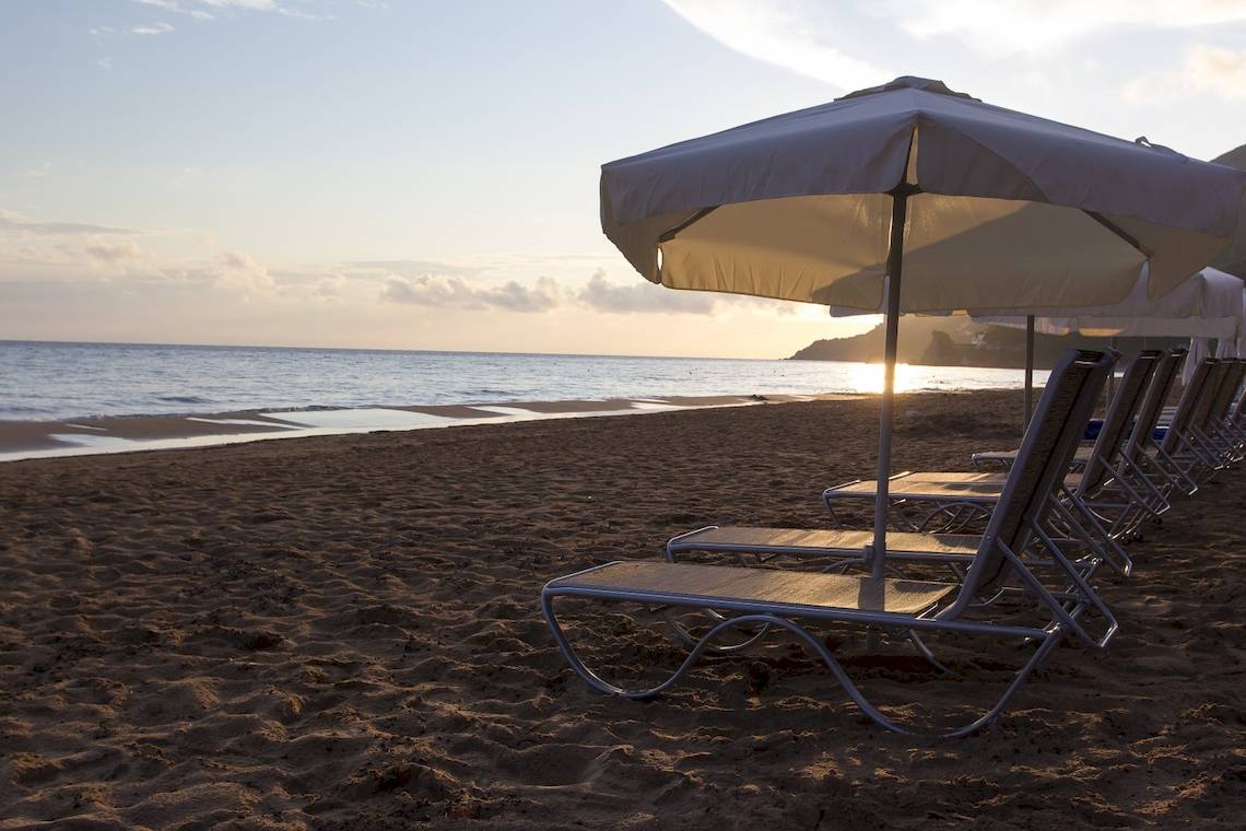 Strand mit Liegen unter Umbrellas am Abend mit Sonnenuntergang
