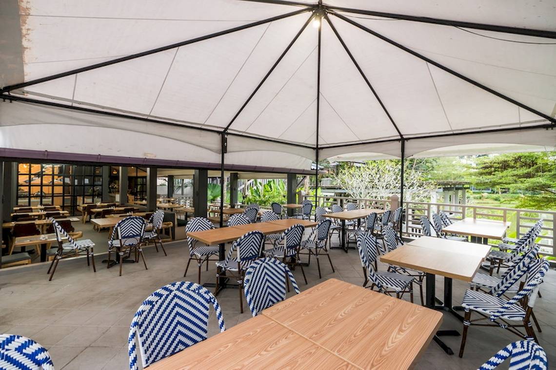 Terrasse des Khao Lak Emerald Beach Resort mit vielen Tischen und Stühlen unter einem Dach.