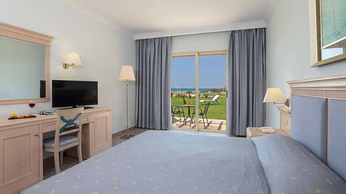 Zimmer im Lindos Princess Beach Hotel mit Meerblick, Bett, Schreibtisch, Fernseher und Glastür.