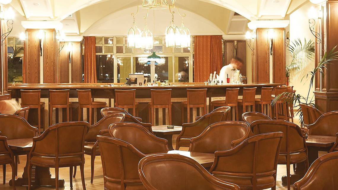 Lounge im Lindos Princess Beach Hotel mit Bar, Holzstühlen und abendlicher Atmosphäre.