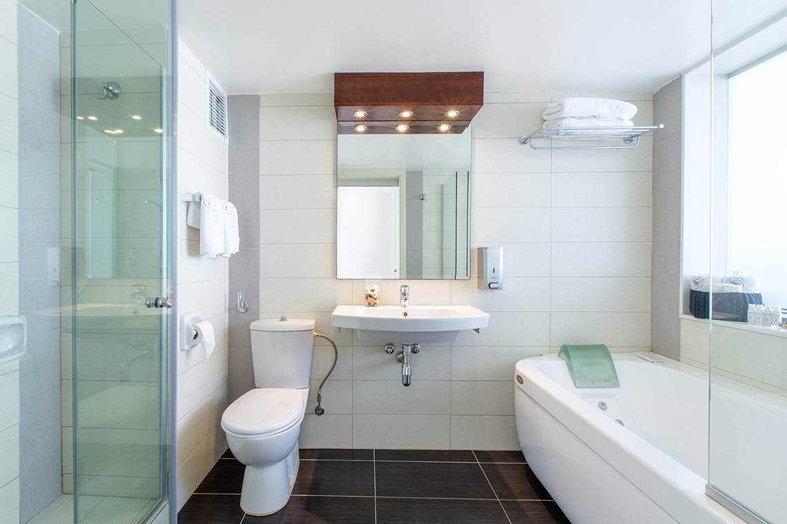 Badezimmer im Lordos Beach Hotel mit Dusche, Badewanne, Toilette und Waschbecken.