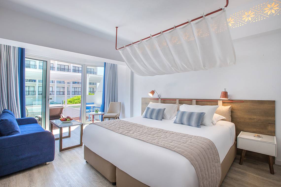 Schlafzimmer im Lordos Beach Hotel mit Doppelbett, Blick auf die Terrasse und Obsttablett auf dem Nachttisch