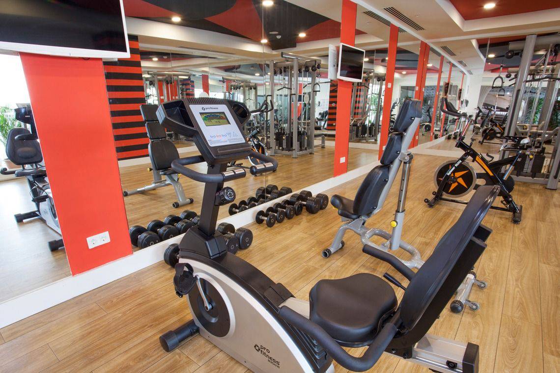 Fitnessstudio im Side Orange Palace Hotel mit Spinnrädern und Hanteln vor einem großen Spiegel.