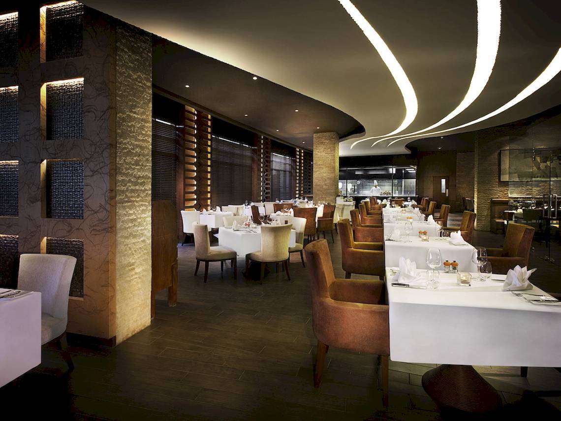 Innenansicht des Restaurants im Sofitel Dubai The Palm mit gedeckten Tischen und eleganter Beleuchtung.