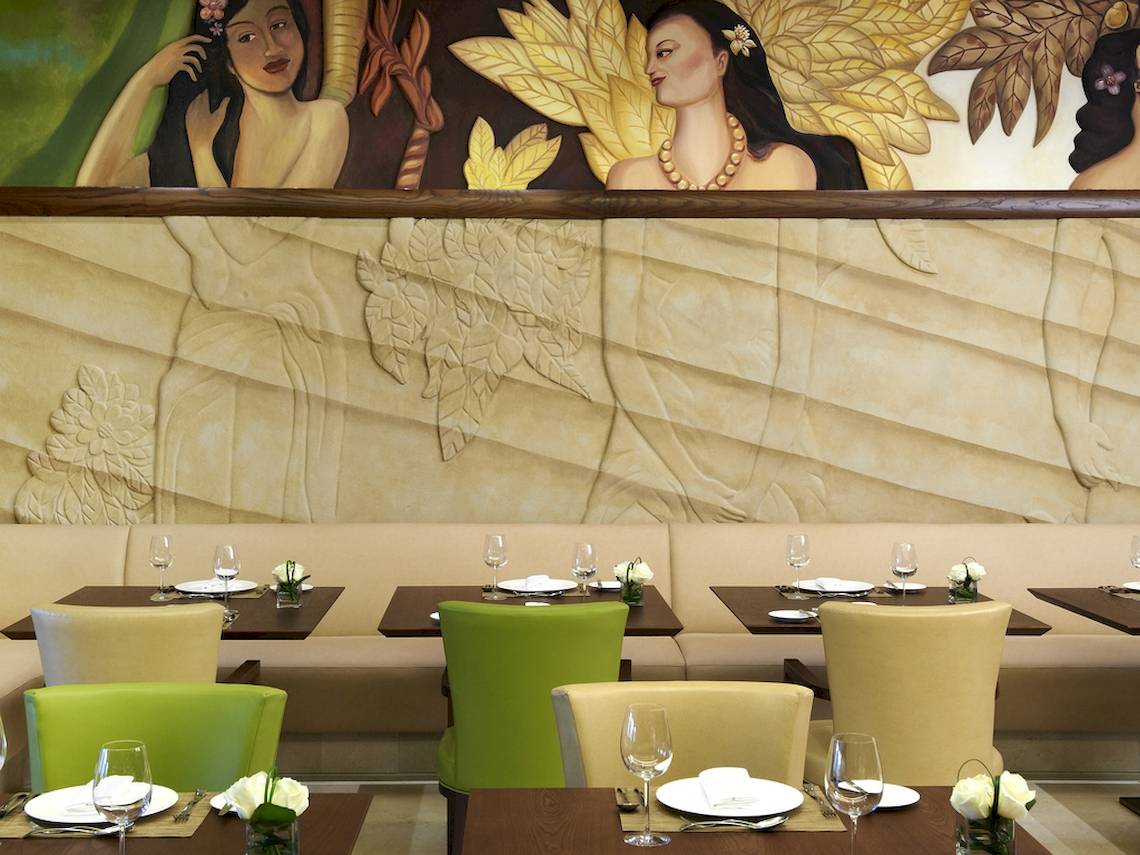Innenansicht des Restaurants im Sofitel Dubai The Palm mit kunstvollen Wandmalereien und gedeckten Tischen.