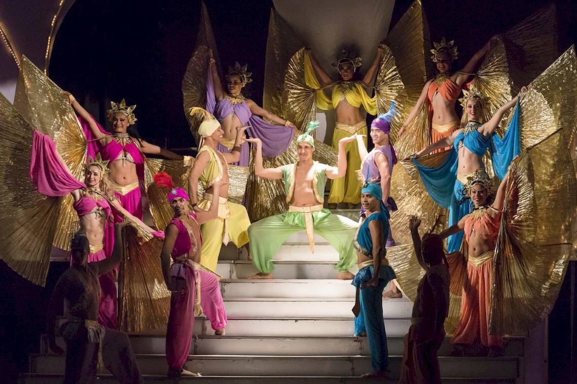 Orientalische Tanzgruppe auf der Bühne mit farbenfrohen Kostümen und goldenen Flügeln.