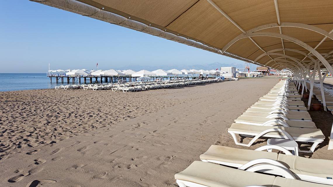 Strand mit Sonnenliegen unter Sonnenschirmen im Miracle Resort