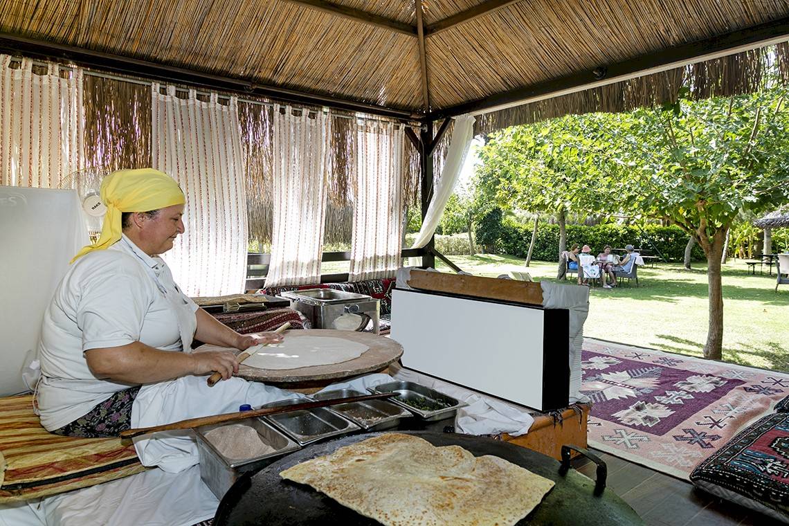 Frau in weißer Kleidung backt Fladenbrot im Garten des Miracle Resorts.