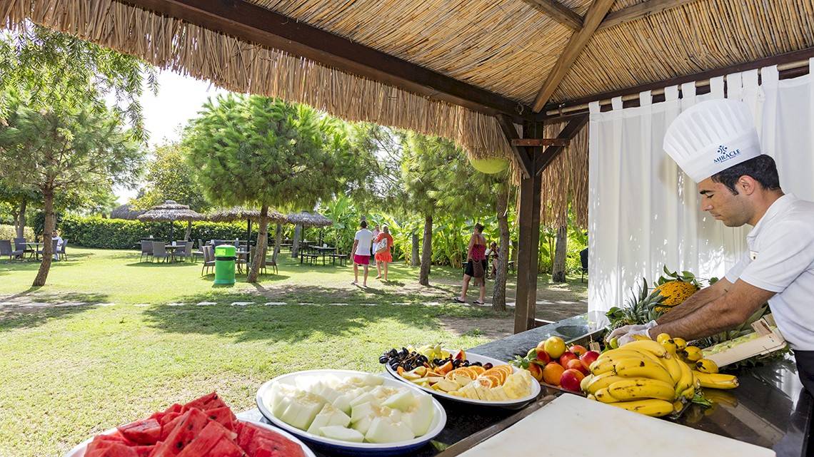 Mann im Miracle Resort, der auf der Terrasse ein Frühstück vorbereitet