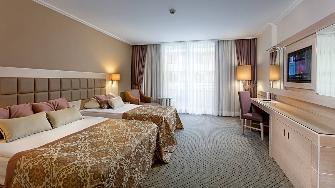 Doppelzimmer im Miracle Resort mit zwei Betten, Schreibtisch, Stühlen und Fernseher.