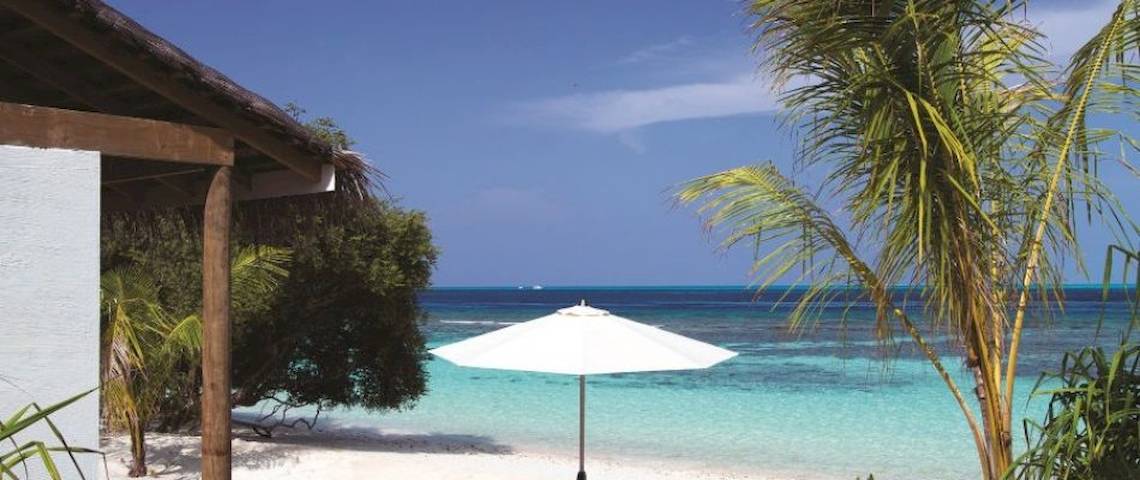Strand des OBLU NATURE Helengeli Hotels mit weißem Sonnenschirm und Blick auf das Meer.