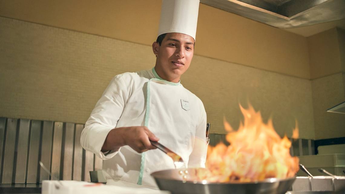 Koch im Coral Level at Iberostar Selection Cancun benutzt ein Wok um Gerichte zuzubereiten