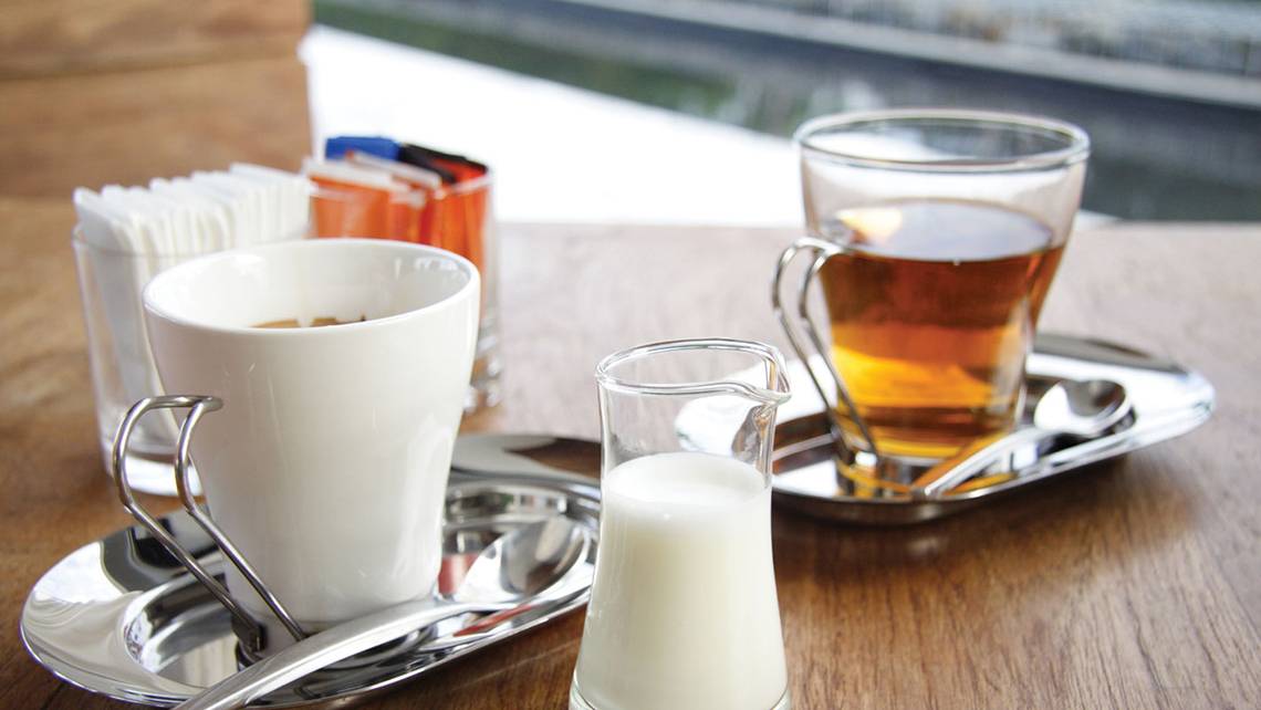 Ein Bild von zwei Tassen Kaffee und Milch auf einem Holztisch.