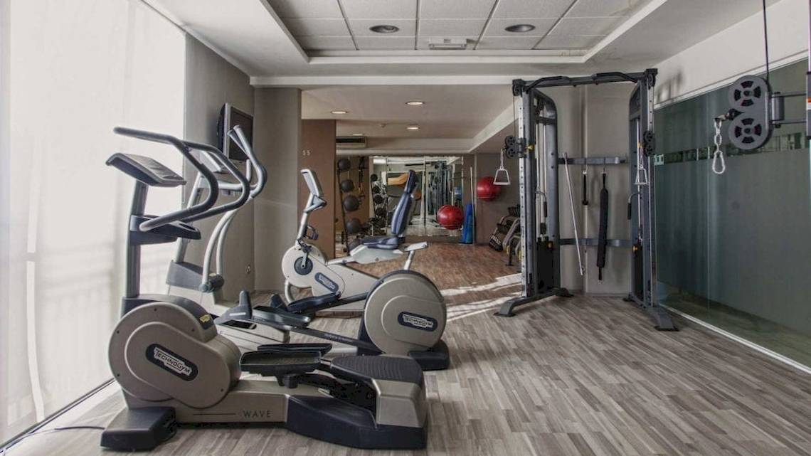 Fitnesscenter im AX The Palace Hotel mit Laufbändern, Ellipsentrainern und Hantelbank.