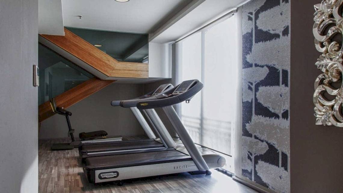 Fitnessraum im AX The Palace Hotel mit zwei Laufbändern und einer Treppe im Hintergrund.