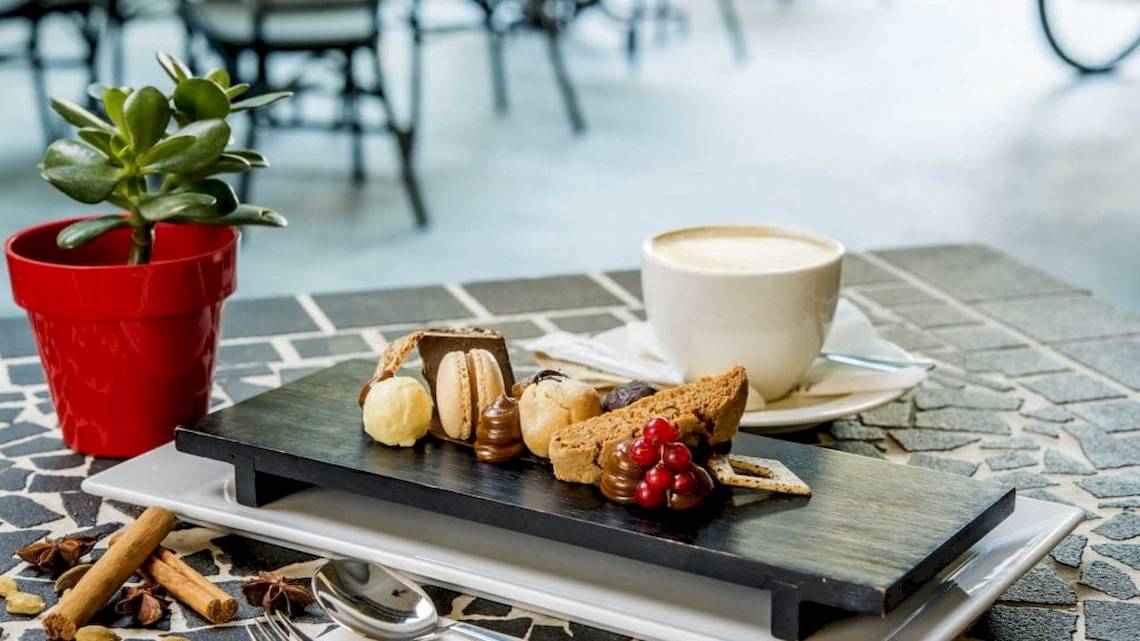 Dessertplatte mit verschiedenen Leckereien, Kaffee und einer Pflanze im AX The Palace