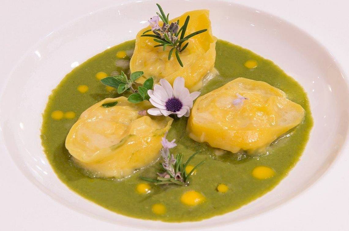 Gericht in einem weißen Teller mit grüner Sauce und Blumen