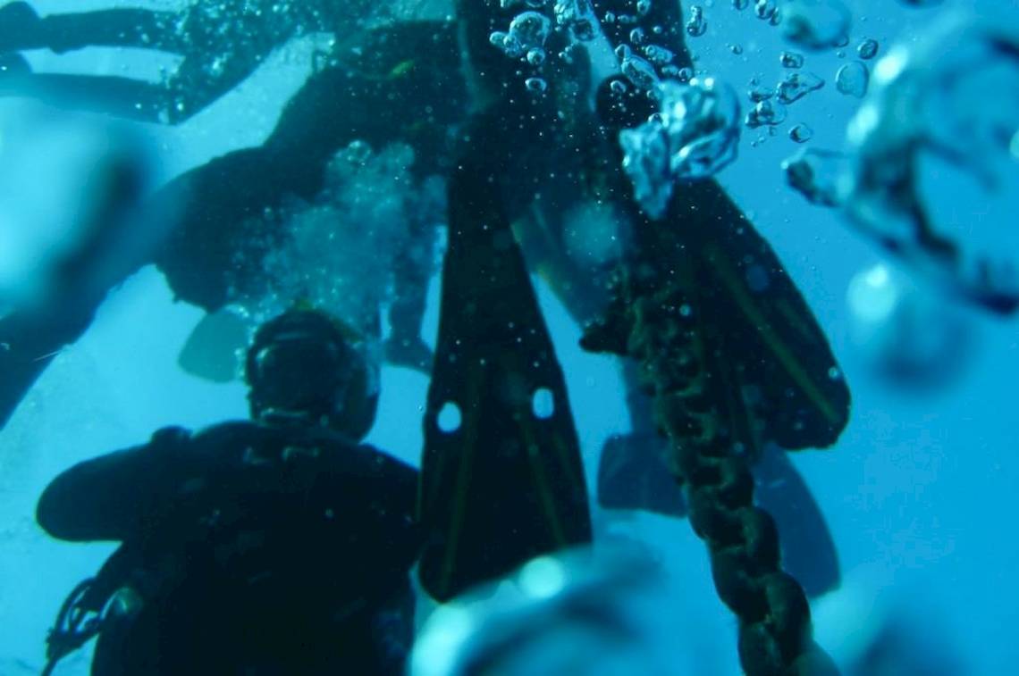 Taucher im Hotel Ollastu Resort, die unter Wasser nach unten schauen.
