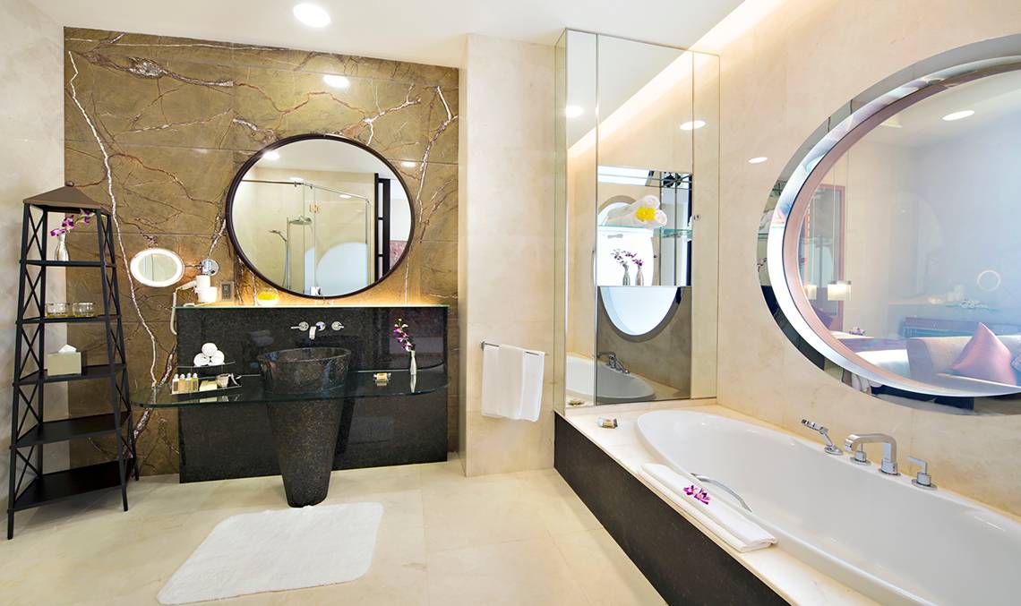 Badezimmer im Al Raha Beach Hotel mit Badewanne, Spiegeln und Waschbecken.