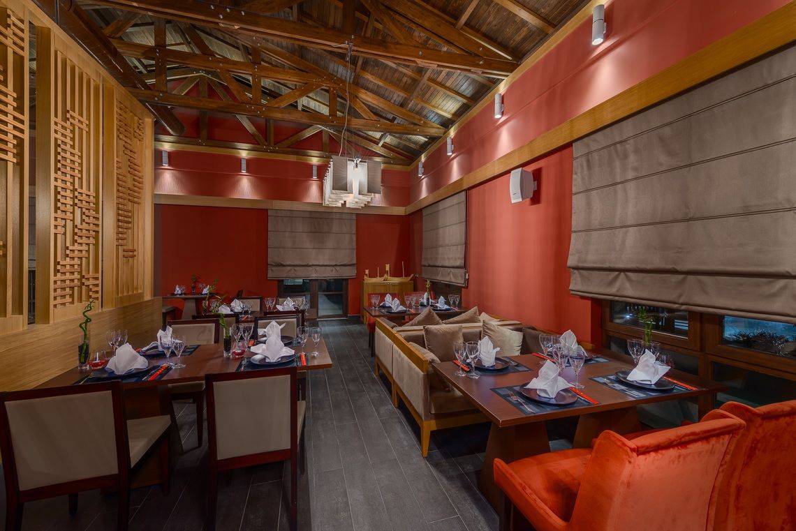 Innenbereich des Rixos Premium Tekirova Hotels, zeigt ein stilvolles Restaurant mit roten Wänden und Holzbalken.