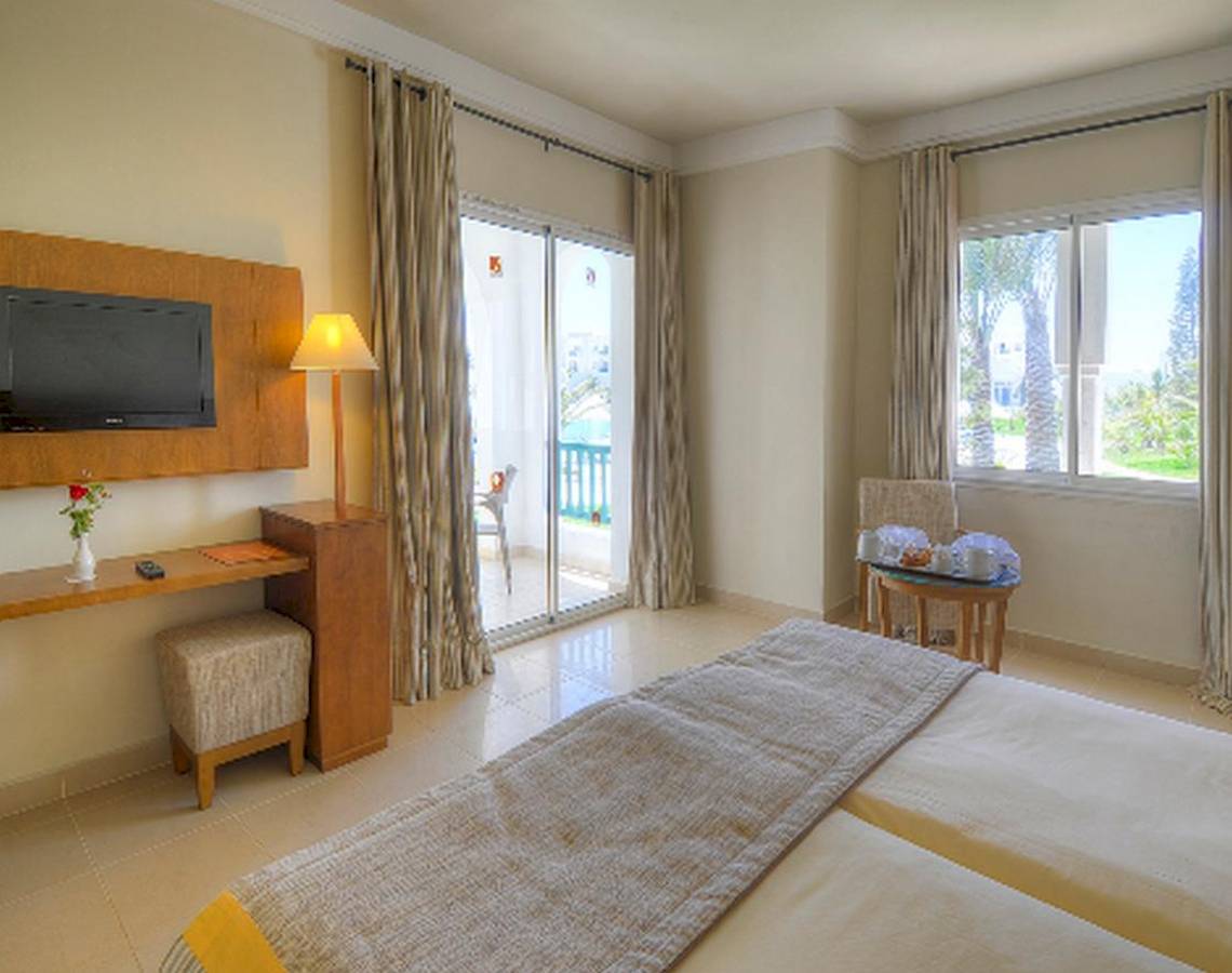 Doppelzimmer mit Balkon im Vincci Helios Beach Hotel, inklusive Fernseher, Schreibtisch, bequemen Betten und Blick auf den Garten.