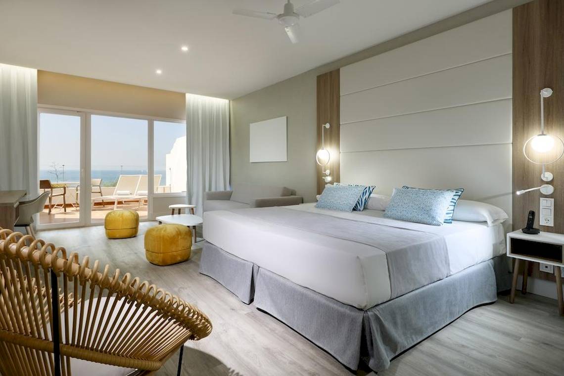 Innenansicht eines Schlafzimmers im Playabonita Hotel mit einem großen Bett und Blick auf das Meer.