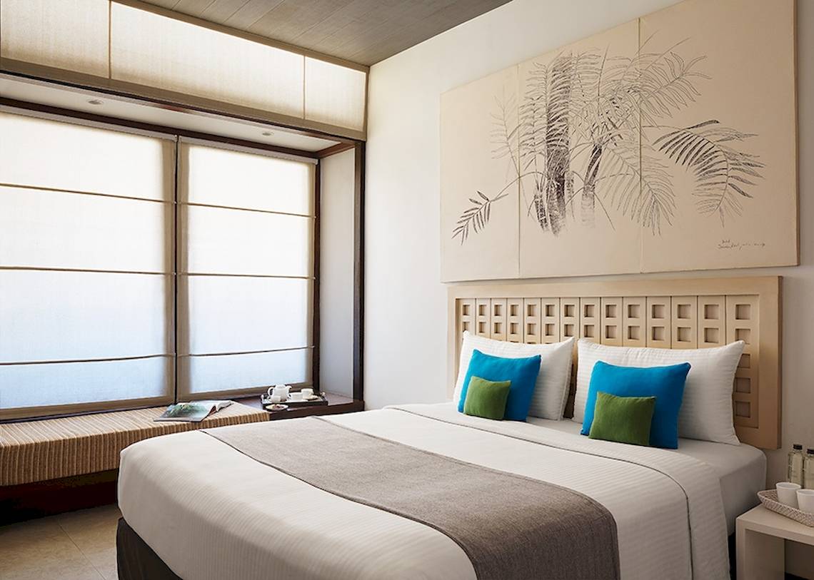 Innenansicht eines Hotelzimmers von Jetwing Blue mit großem Bett, Kunstwerk an der Wand und Fenstern.
