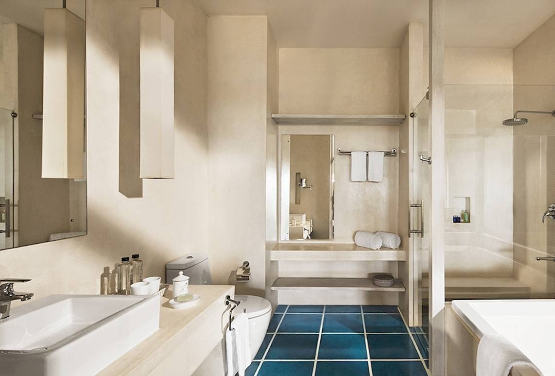Innenansicht des Badezimmers im Jetwing Blue Hotel mit blauen Kacheln, einer Badewanne, einer Dusche und einem Waschbecken.