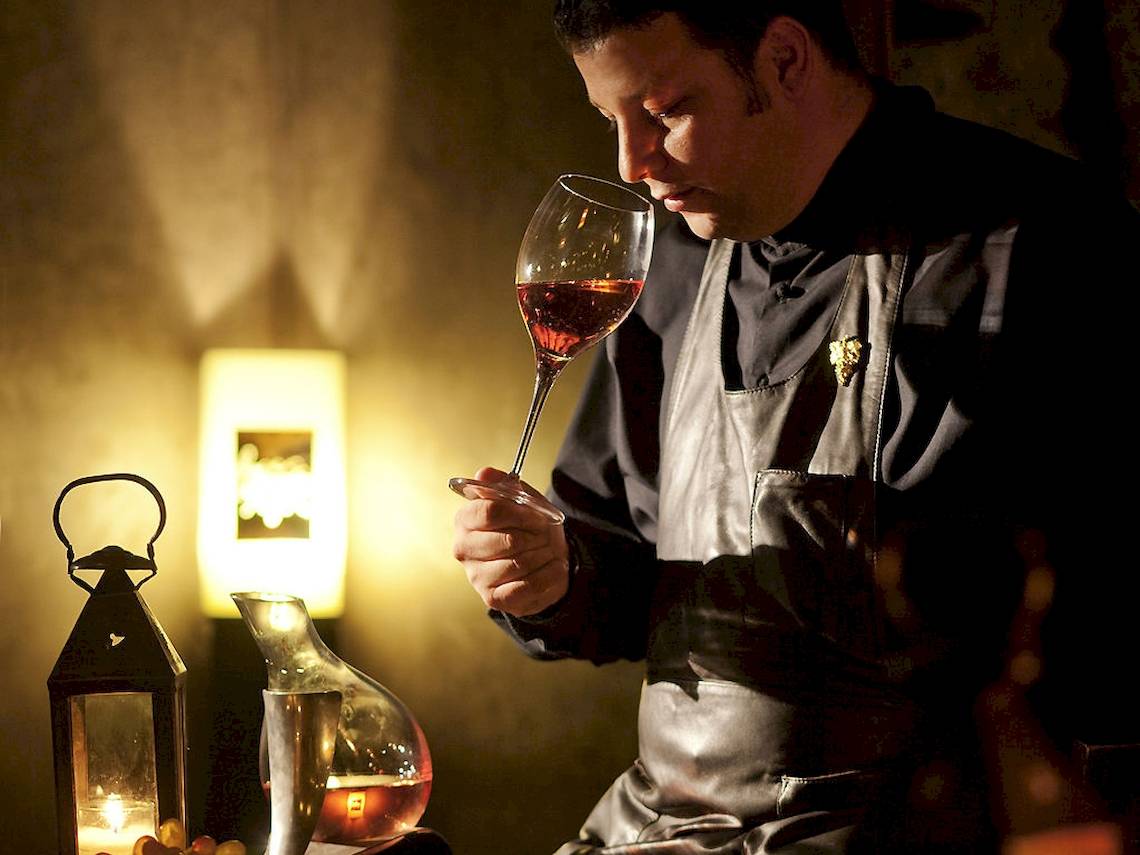 Mann der Sofitel Marrakech Lounge & Spa Wein kostet in einem dunklen Raum