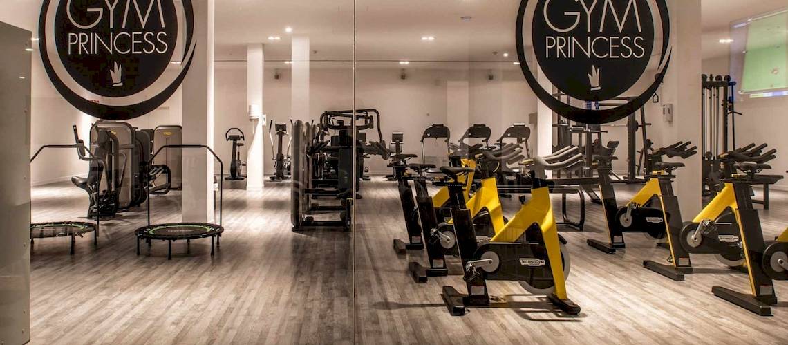 Innenansicht des Gyms der Guayarmina Princess mit diversen Fitnessgeräten und einem Holzboden.