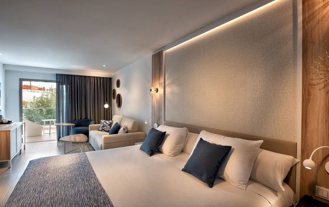 Guyarmiina Princess Hotel Schlafzimmer mit Doppelbett, Kissen, Couch und Glastür.