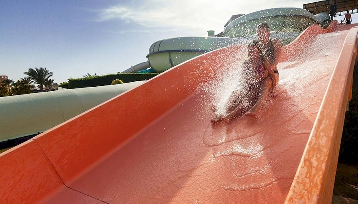 Zwei Personen rutschen auf einer roten Wasserrutsche im JAZ Neo Dar El Madina Hotel.