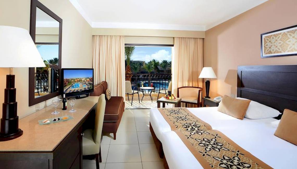 Hotelzimmer im Jaz Dar El Madina mit Balkon, Fernseher, Schreibtisch und Möbeln.