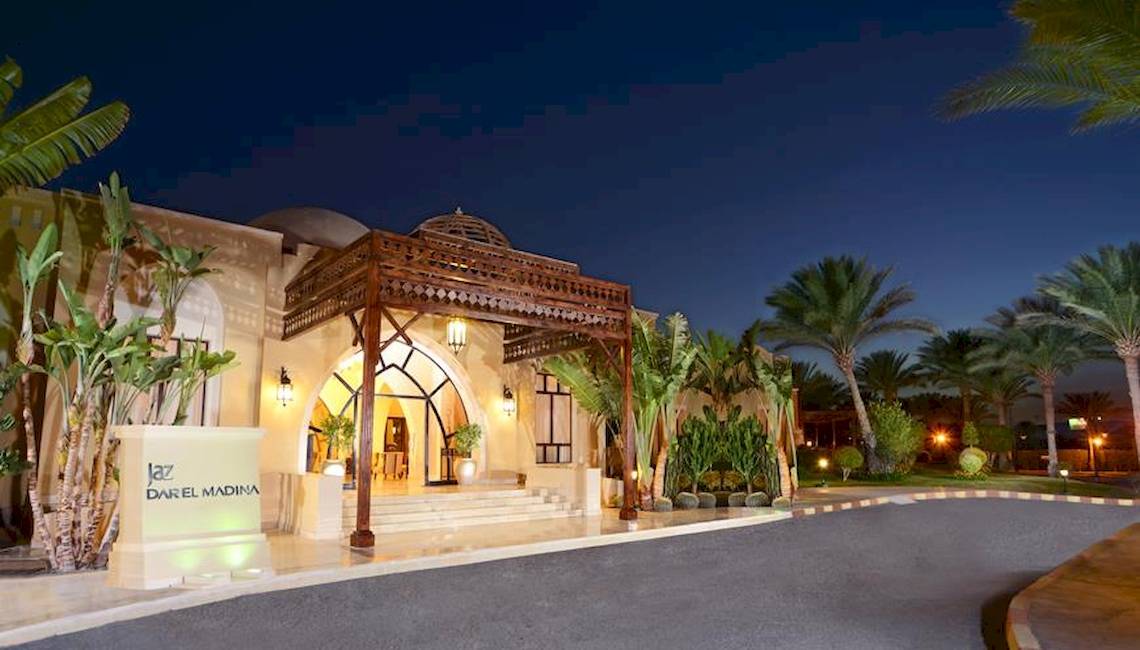 Außenansicht des Jaz Dar El Madina Hotels bei Nacht mit einer gepflasterten Einfahrt und einem illuminierten Eingang.