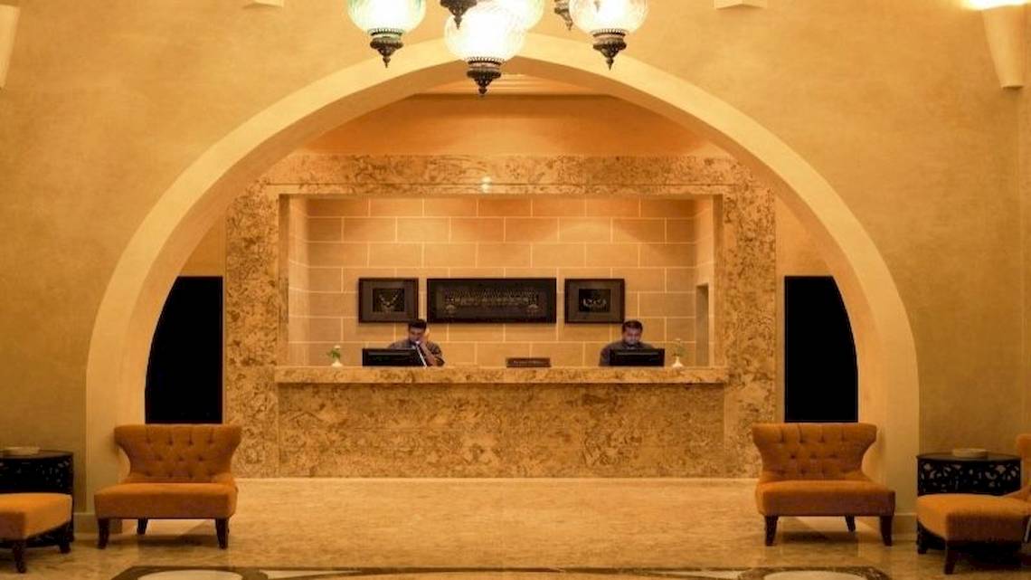 Rezeption des Jaz Dar El Madina Hotels mit zwei Mitarbeitern hinter dem Empfangstresen.