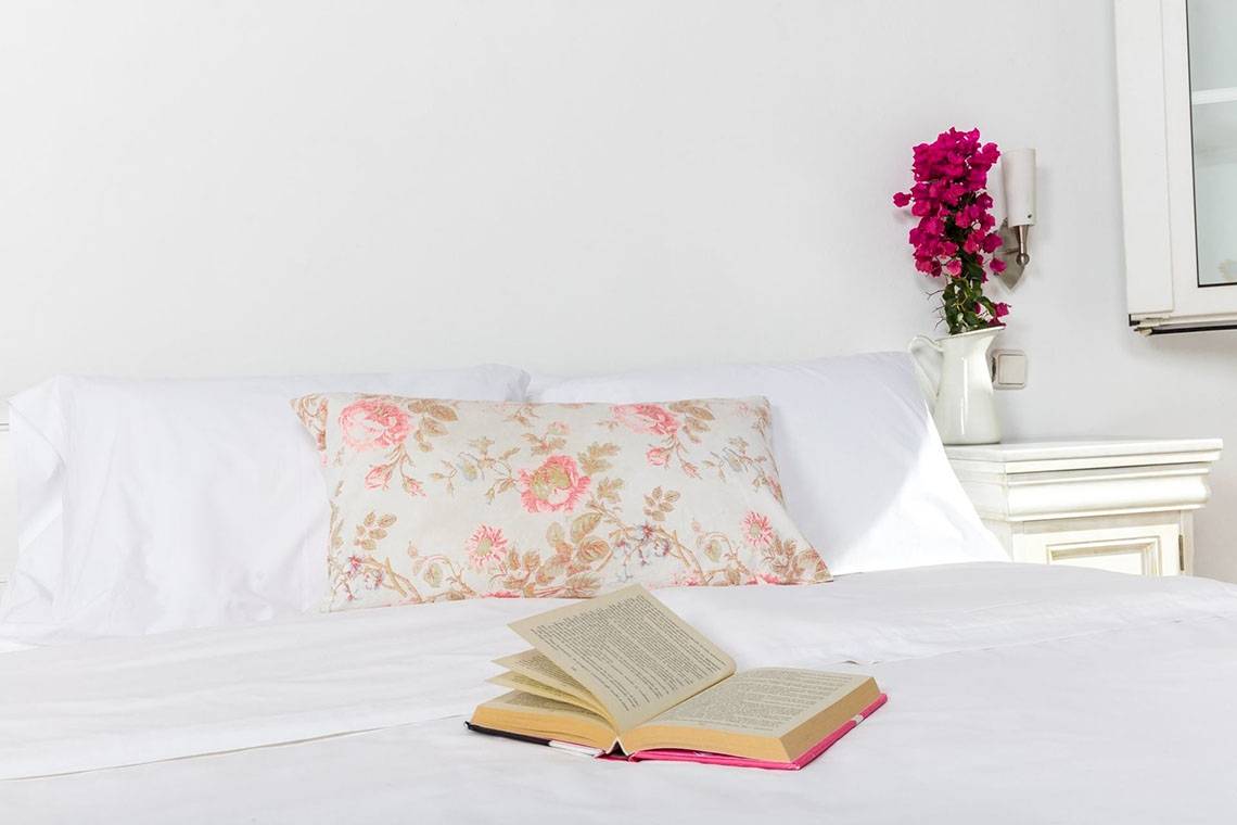 Ein Bett mit weißen Kissen und einem offenen Buch auf der Bettdecke.