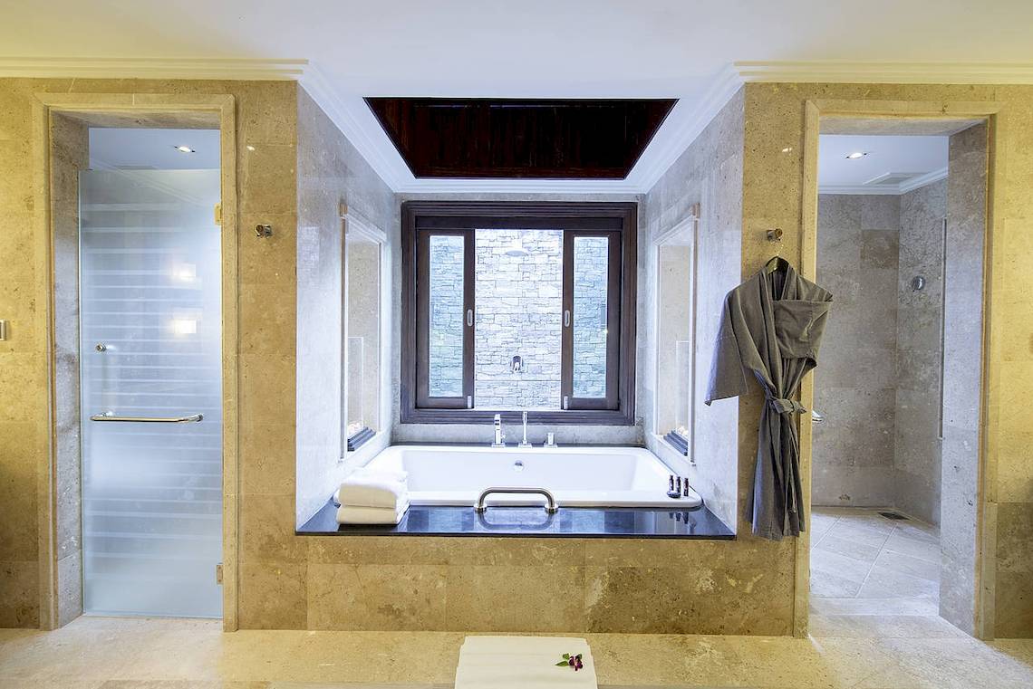 Das Badezimmer des Robinson Khao Lak Hotels mit Badewanne, Fenster und Handtuch.
