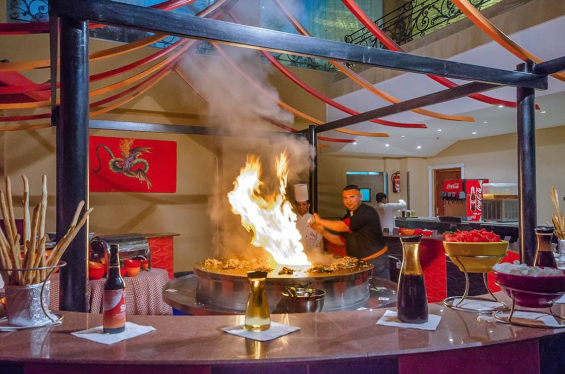 Ein Koch am Arbeitsplatz im Titanic Palace Hotel mit einer brennenden Flamme und Speisen.