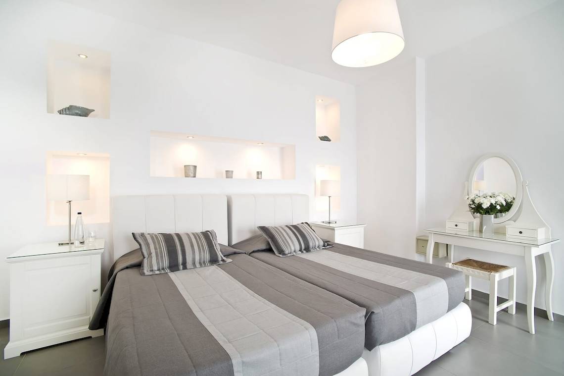 Doppelbett-Zimmer im Agali Houses Hotel mit weißen Möbeln und grauen Laken.