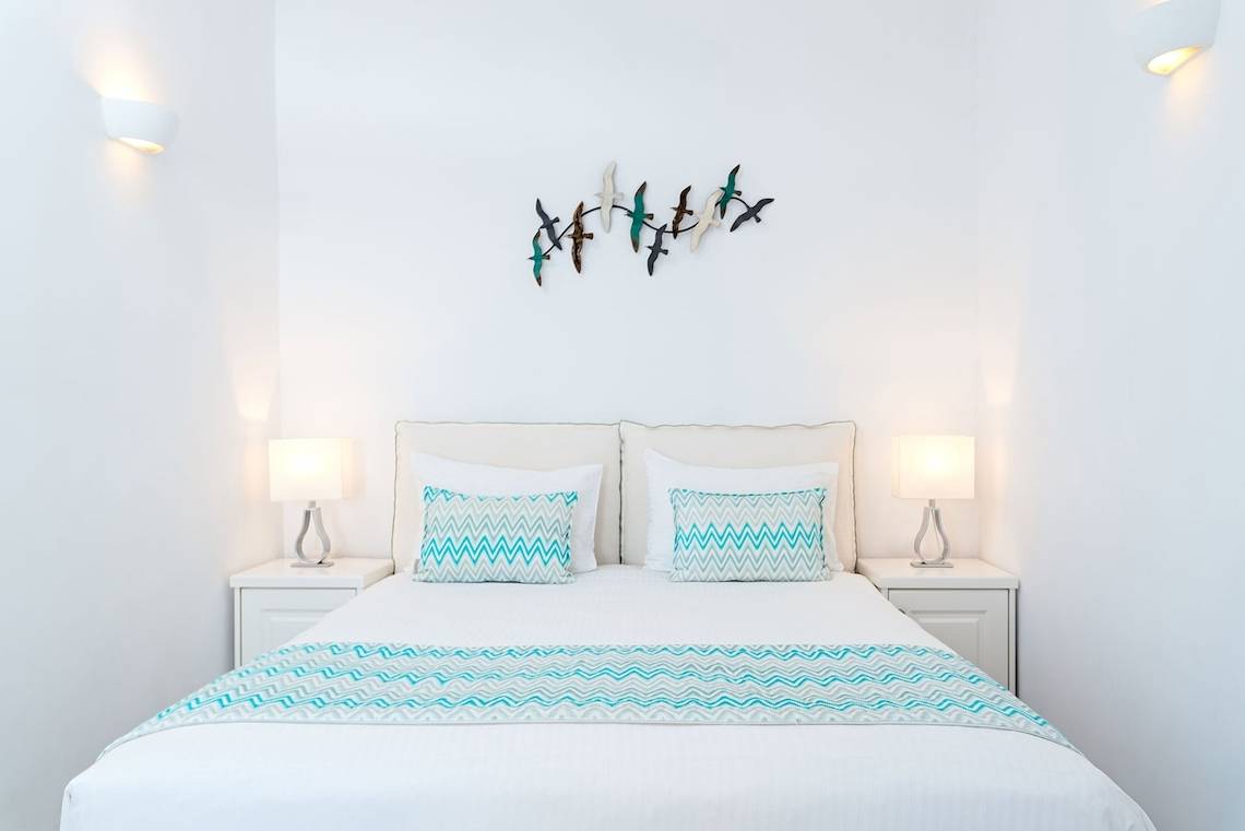 Schlafzimmer von Agali Houses mit weißen Wänden, einem Doppelbett und zwei Nachttischen mit Lampen.