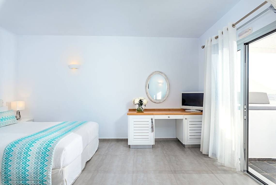 Innenansicht eines Zimmers der Agali Houses mit Bett, Schreibtisch und Fernseher.
