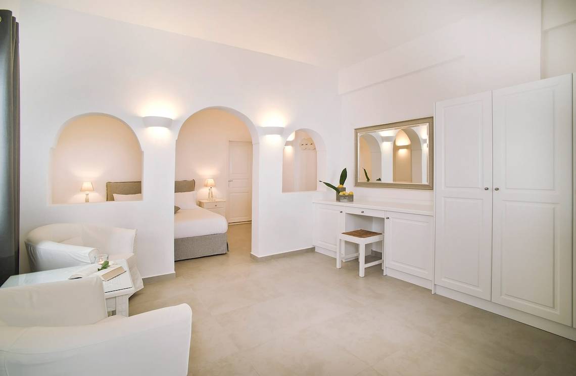 Innenansicht der Suite im Agali Houses Hotel mit weißen Möbeln, einem großen Bett und einer hellen Atmosphäre.
